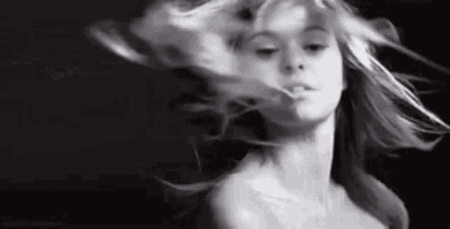 a black and white photo of a woman with her hair blowing in the wind