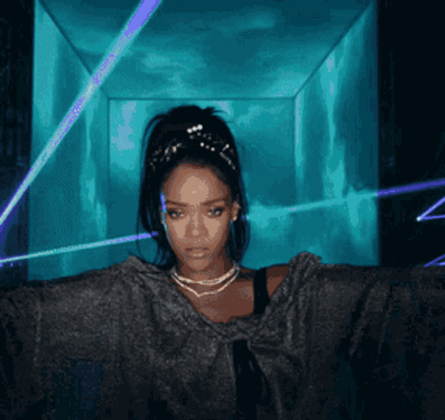 a woman with a ponytail and a necklace stands in front of a blue light