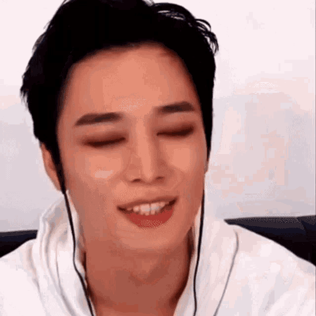 a young man wearing headphones is smiling with his eyes closed .