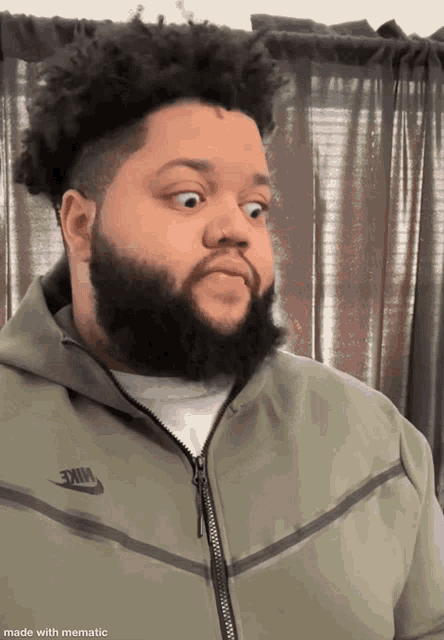 a man with a beard wearing a nike jacket makes a surprised face