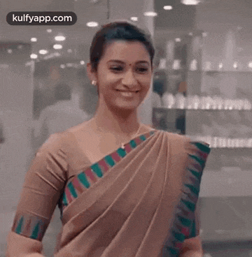 a woman in a saree is smiling and looking at the camera in a store .