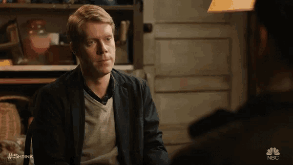 a man in a suit talks to another man in a scene from nbc 's show shrink