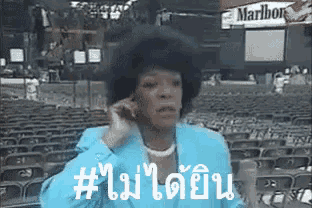 a woman in a blue suit is talking on a cell phone with a marlboro sign in the background .