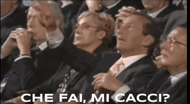 a group of people sitting in a row with the words che fai mi cacci written on the bottom
