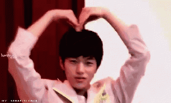 a young boy making a heart shape with his hands