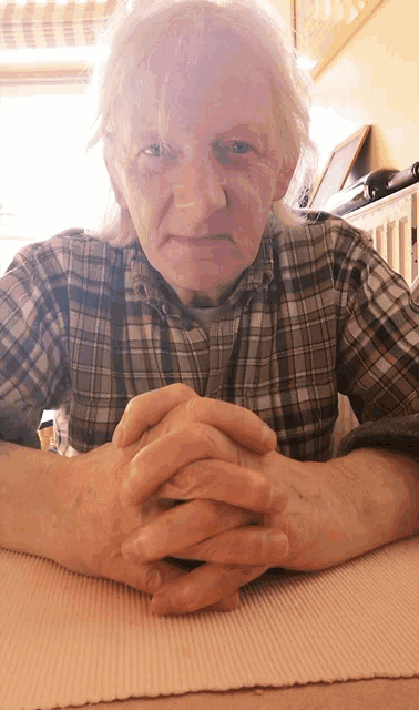 a man in a plaid shirt has his hands folded