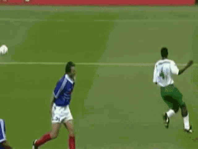 a man in a blue jersey with the number 12 on it is kicking a soccer ball