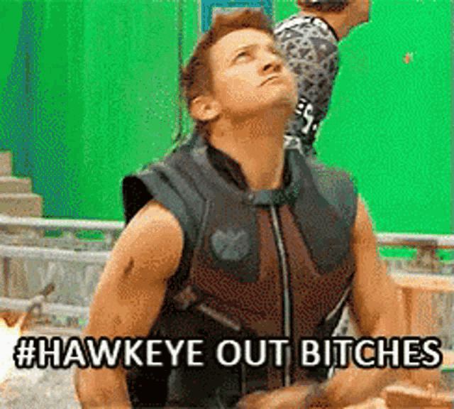 a man in a hawkeye vest is standing in front of a green screen and says hawkeye out bitches .