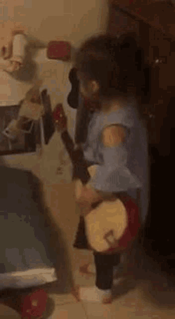 a little girl is playing an ukulele in a room .