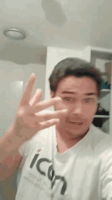 a man wearing an icon t-shirt is making a peace sign