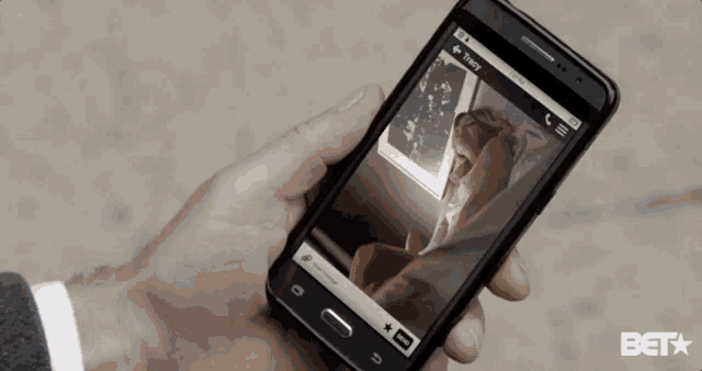a person is holding a cell phone with a picture of a man on the screen