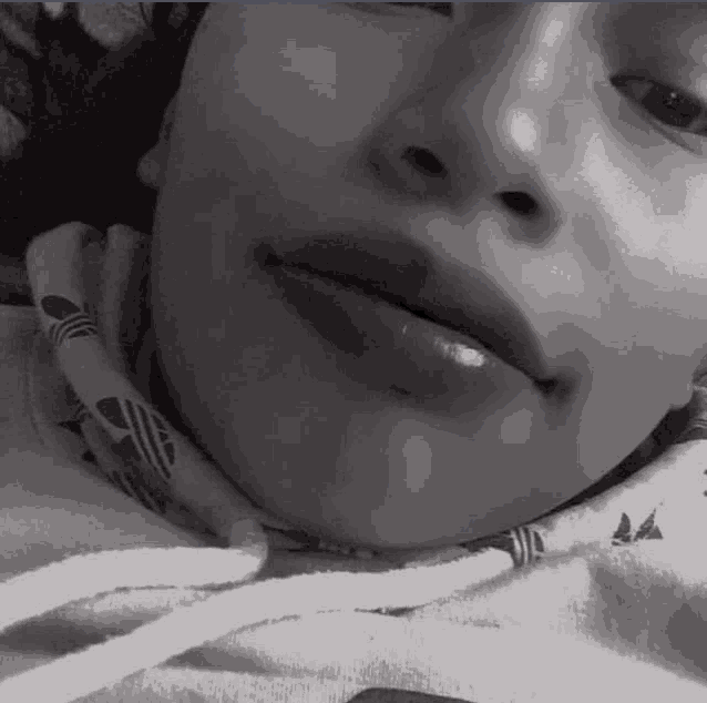 a black and white photo of a woman laying down with her eyes closed and her mouth open .