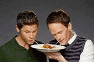 two men are eating food with straws from a plate .