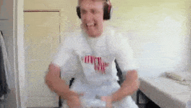 a man wearing headphones and a white shirt is playing a video game with a controller .