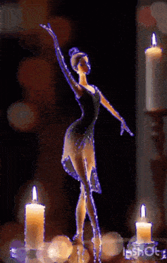 a statue of a ballerina stands in front of candles