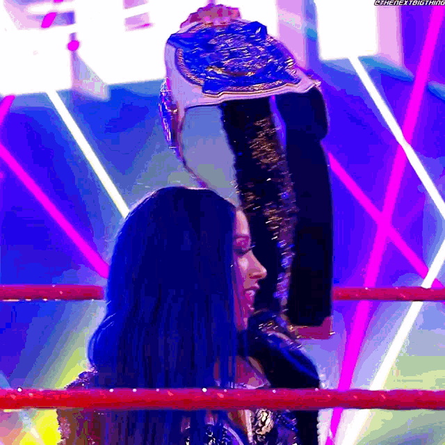 a woman in a wrestling ring holds up a championship belt with the hashtag #catchthetrend