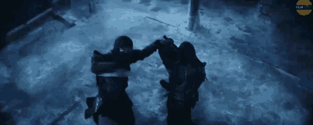 a couple of people are standing next to each other in the dark holding hands .