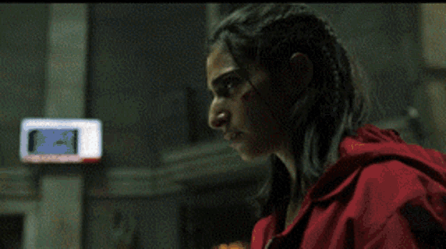a bald man with a beard wearing a red jacket is holding a gun .