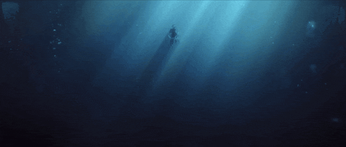 a person swimming in the ocean with the sun shining through