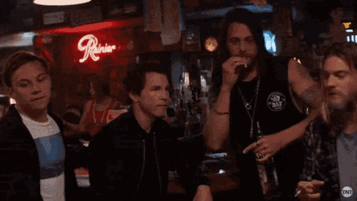 a woman is taking a picture of a group of men in a bar with a cell phone .