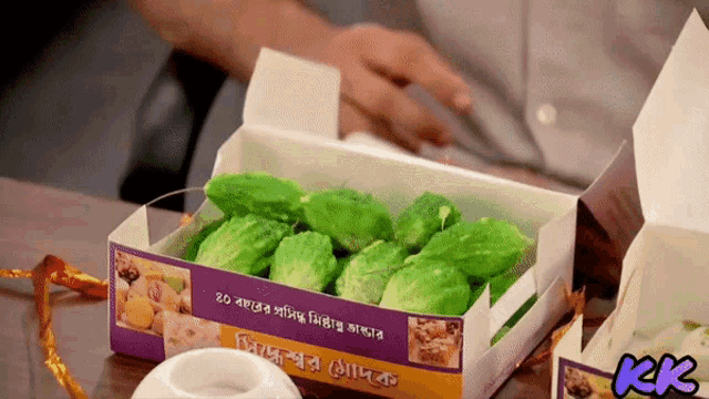 a box of green vegetables has a purple label that says kk