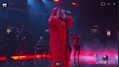 a woman in a red dress singing into a microphone on a stage