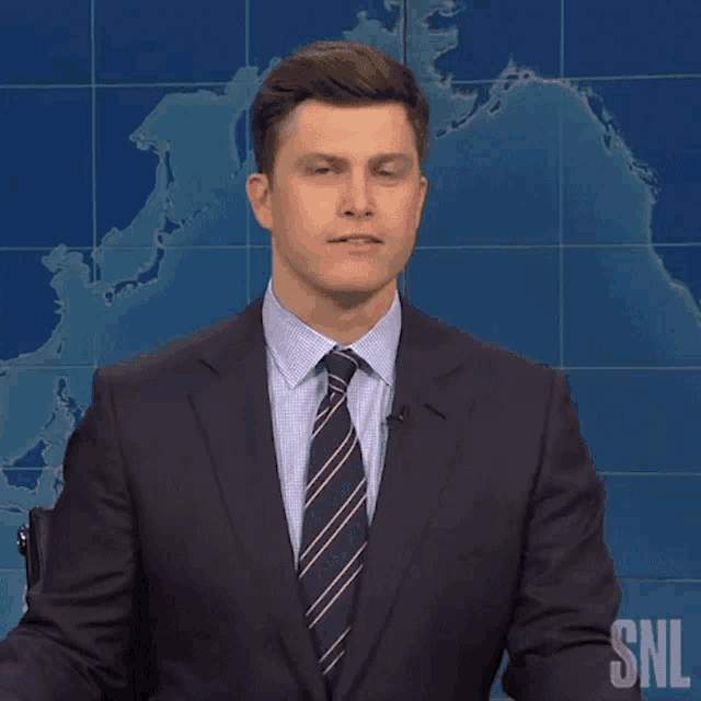 a man in a suit and tie says wow in front of a world map