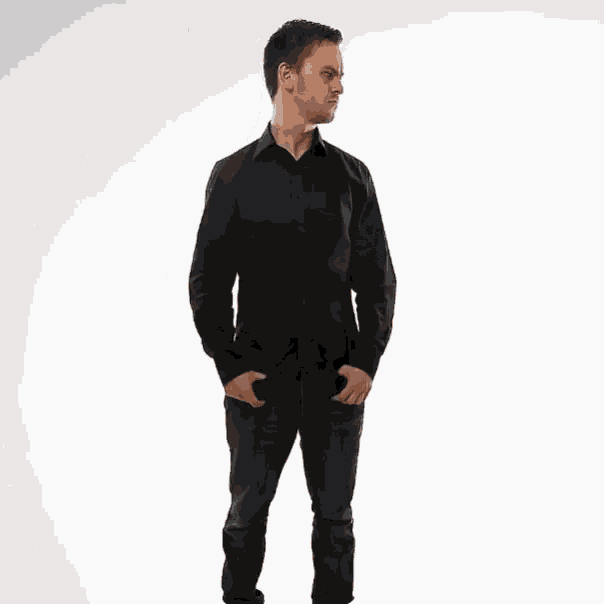 a man in a black shirt and jeans is making a stop gesture