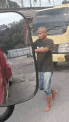 a man is walking barefoot in front of a truck in a rear view mirror
