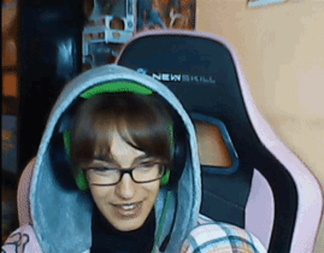 a girl wearing glasses and headphones is sitting in a chair that says newskill