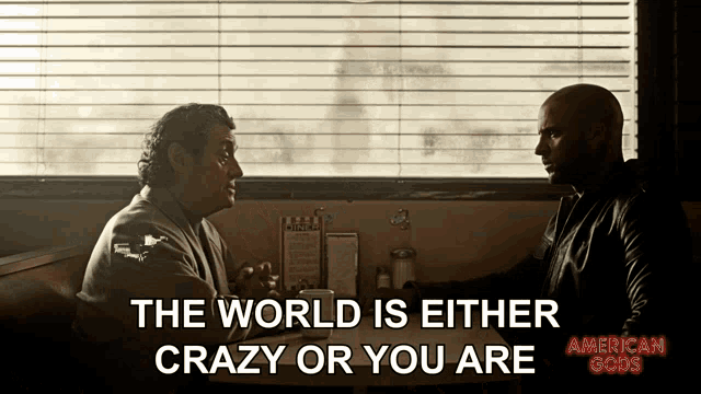 two men are sitting at a table with the words the world is either crazy or you are