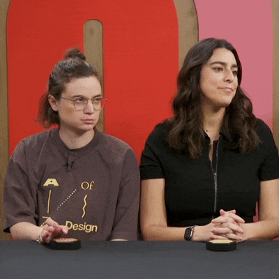 two women sitting at a table with one wearing a shirt that says a of design