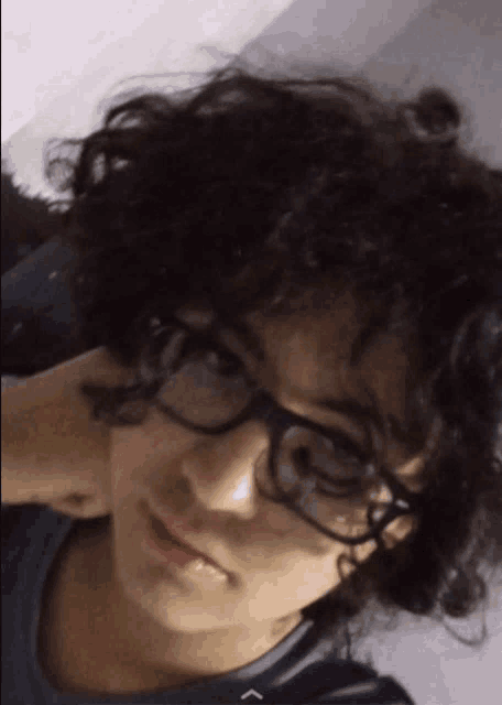a young man with curly hair wearing glasses