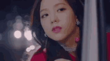 a close up of a woman 's face wearing a red dress and earrings .