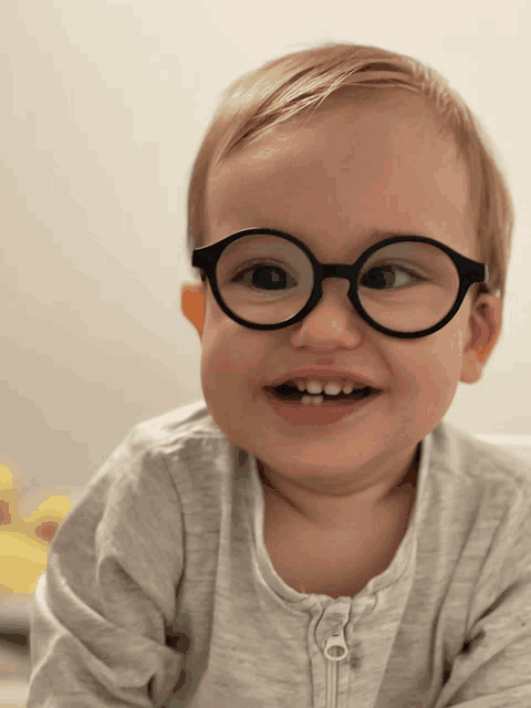 a baby wearing glasses and a grey sweater