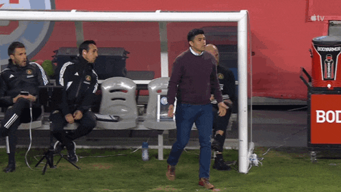 a man walking on a soccer field next to a sign that says bodyarmor