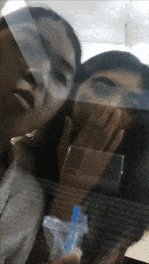 a woman covering her mouth with her hand while another woman holds a cell phone
