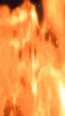 a group of people are standing around a large fire
