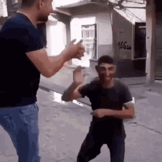 a man with a mask on his face is dancing with another man on a street .