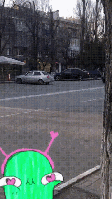 a drawing of a green alien with a pink antenna on its head is on the sidewalk in front of a street