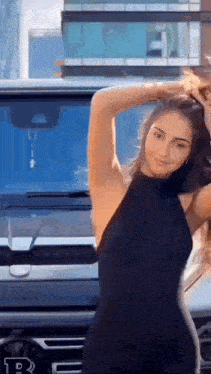 a woman in a black dress is standing in front of a mercedes benz g63 .