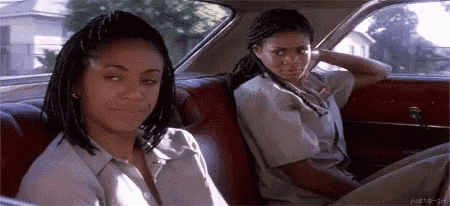 two girls are sitting in the back seat of a car .