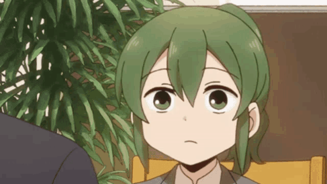 a cartoon character with green hair and big eyes looks at the camera