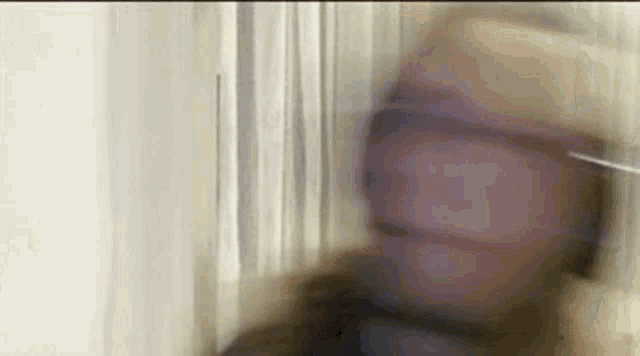 a blurry picture of a man standing in front of a window .
