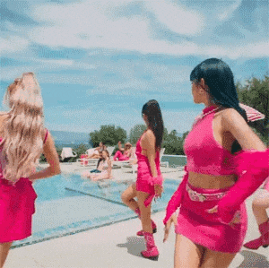 a group of women in pink dresses are dancing around a pool .