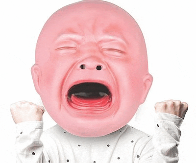 a baby wearing a pink crying mask with his mouth open and his fist in the air .
