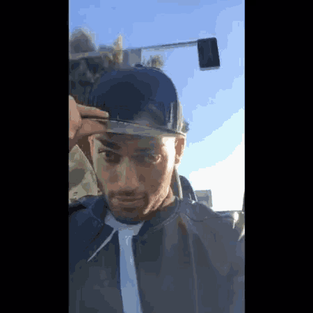 a man wearing a hat and a jacket is standing in front of a street light
