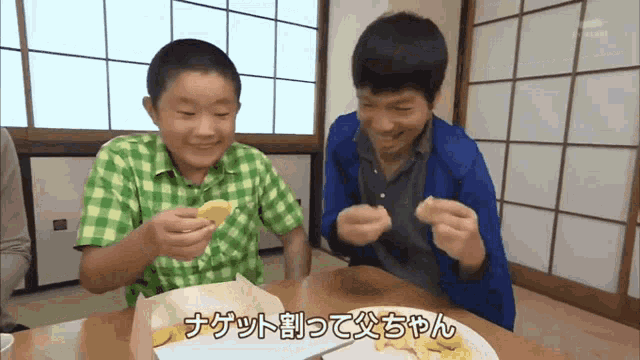 two boys are sitting at a table eating nuggets with chinese writing