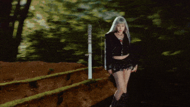 a woman in a black crop top and shorts stands in front of a fence
