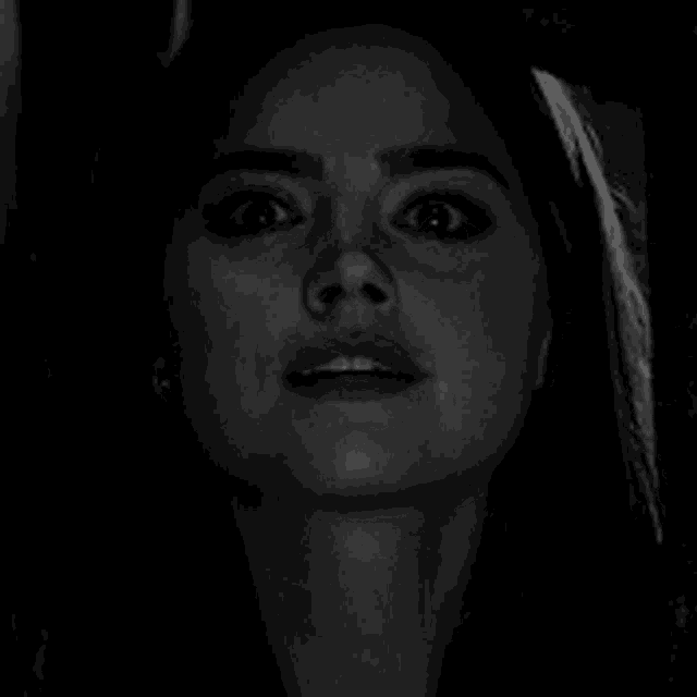 a black and white photo of a woman 's face with a smile on her face .